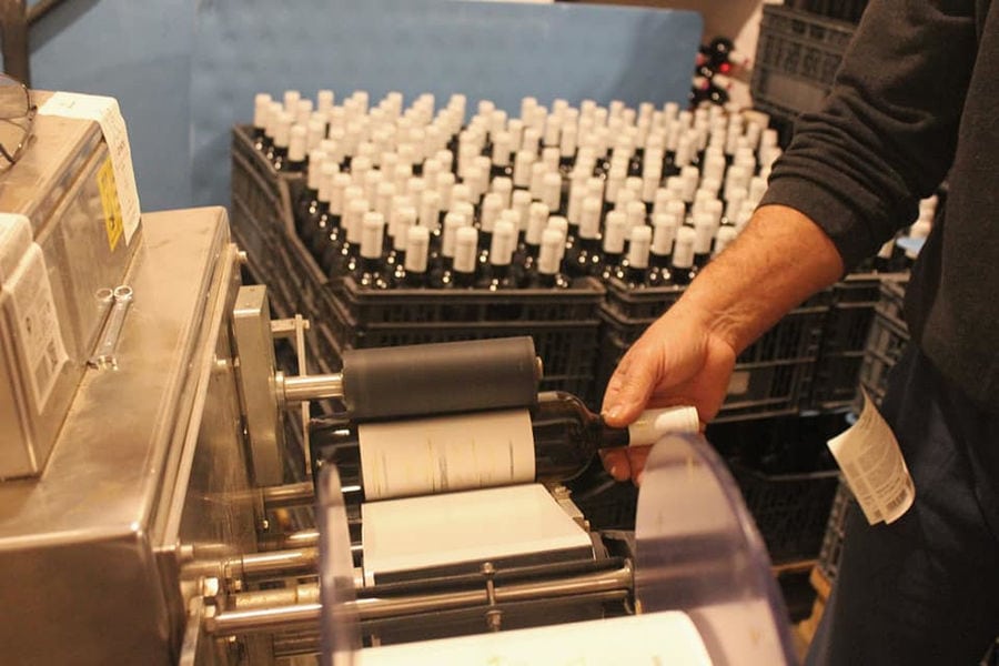 man using wine labeling machine at 'Manalis Winery' facilities